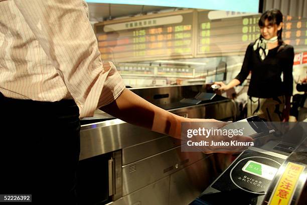 Models walk through a ticket gate of East Japan Railway with a NTT DoCoMo's new mobile phone during a press conference on February 22, 2005 in Tokyo,...