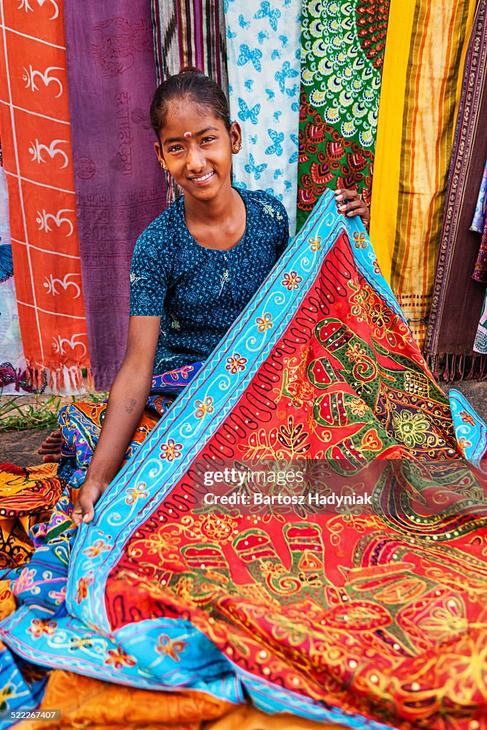 Young Indian girl selling colorful embroidered rug