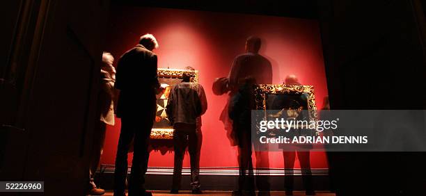 Long shutter exposure shows people admiring the paintings "Sleeping Cupid" and "Portrait of a Knight of Malta" by Caravaggio during the press preview...