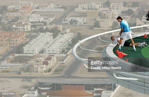 Roger Federer of Switzerland and Andre Agassi of the USA look over the edge of the 700ft high helipad after losing a ball over the side on February...