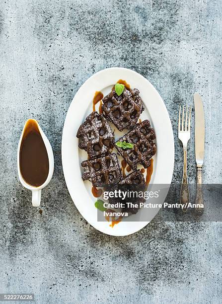 chocolate belgian waffles with salted caramel sauce and mint on white ceramic serving plate over gru - salted brownie stock pictures, royalty-free photos & images