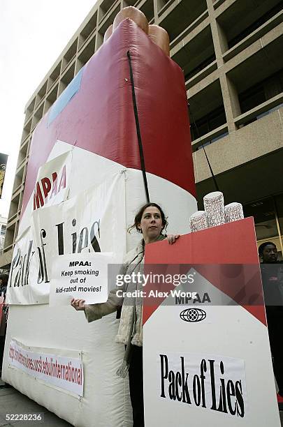 Stephanie Hilborn, with Essential Action, holds posters next to a giant inflatable cigarette pack during a protest against movies that promote...