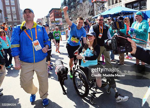 Boston Marathon bombing survivors Patrick Downes and Jessica Kensky celebrate at the finish line with their dog Rescue after Downes completed the...