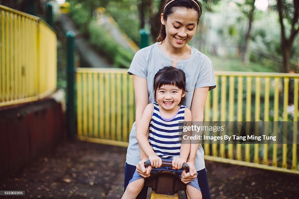 Mom & toddler playing seesaw joyfully in park