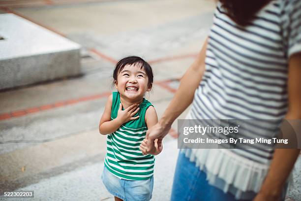 smiling toddler holding hands with mom in park - holding hands kids stock-fotos und bilder