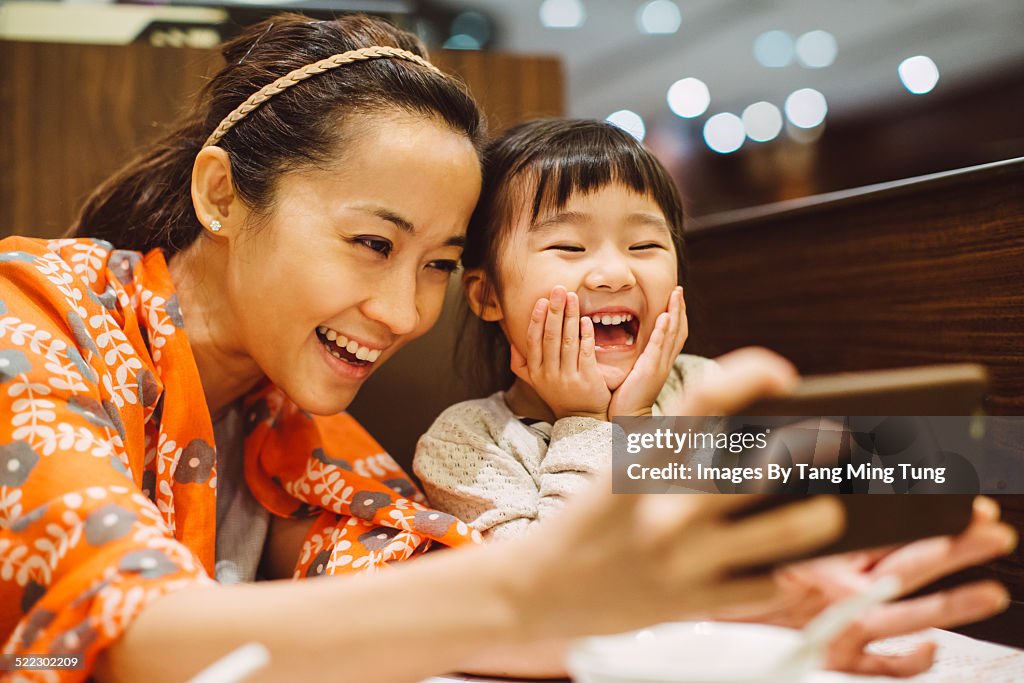 Mom & toddler taking selfies in restaurant