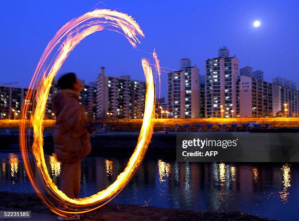 South Korean boy spins a fireball in southern Seoul 23 February 2004 as part of celebrations marking the year's first full moon day, which has been...