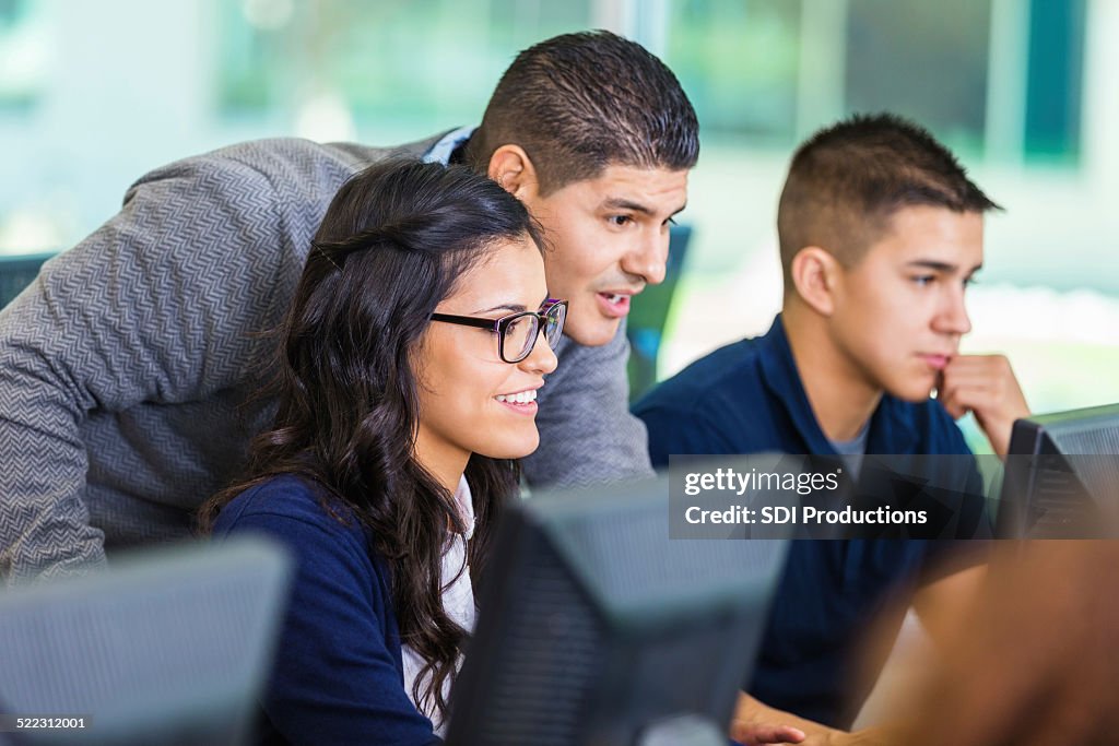 Professor reviewing student's work in private school computer lab