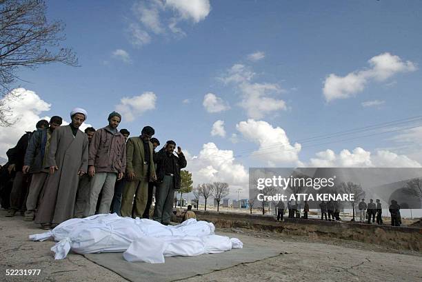 Iranians pray over the corpses of a father, mother and daughter before burial in Beheshte Zahra cemetery in Zarand 23 February 2005, after a powerful...