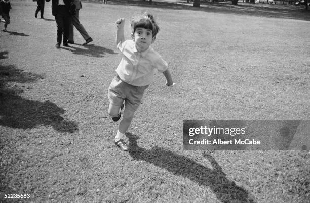 John F Kennedy Jr takes a dislike to photographer Albert McCabe in Green Park. London, 13th May 1965.