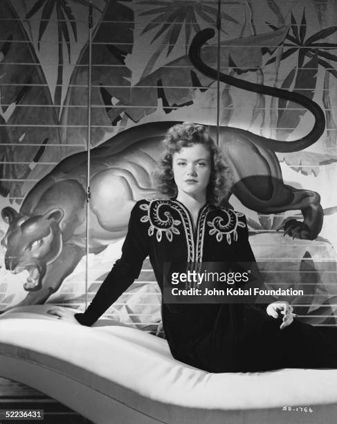 Around the time of her starring role in Jacques Tourneur's 'Cat People', French film actress Simone Simon poses in front of a screen depicting a...