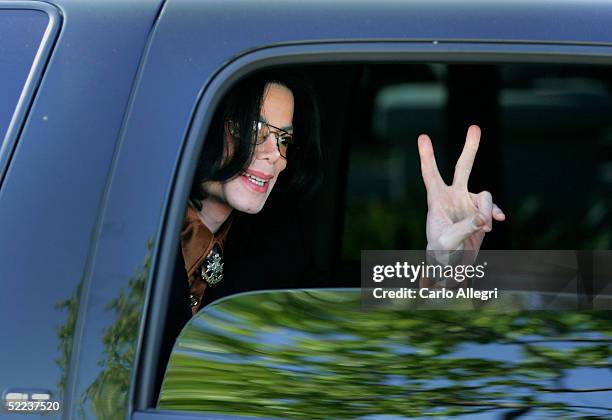 Singer Michael Jackson flashes a "V" sign to fans from inside a vehicle as he departs the Santa Barbara County Courthouse following the jury...