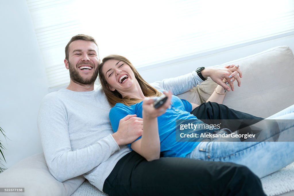 Smiling Couple at Home Watching tv and Lying on Sofa