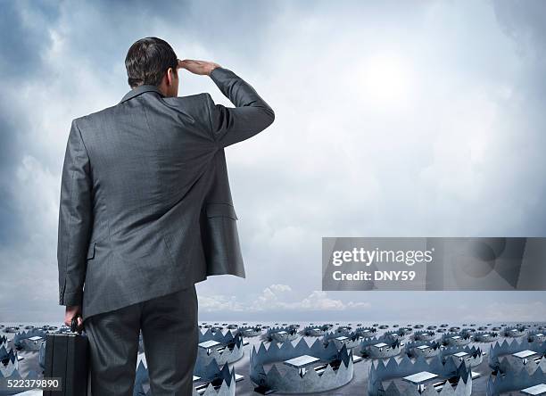 businessman looks out into the distance littered with traps - bear trap stock pictures, royalty-free photos & images