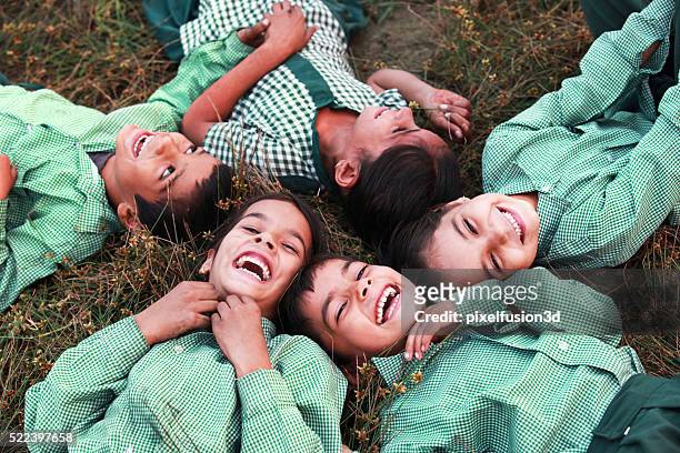 cheerful children lying dawn on grass - rural scene stock pictures, royalty-free photos & images