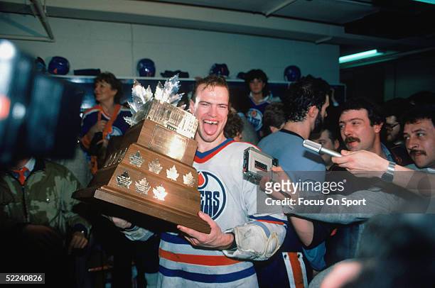 Mark Messier of the Edmonton Oilers holds the Conn Smythe Trophy in the locker room after defeating the New York Islanders for the 1984 Stanley Cup...