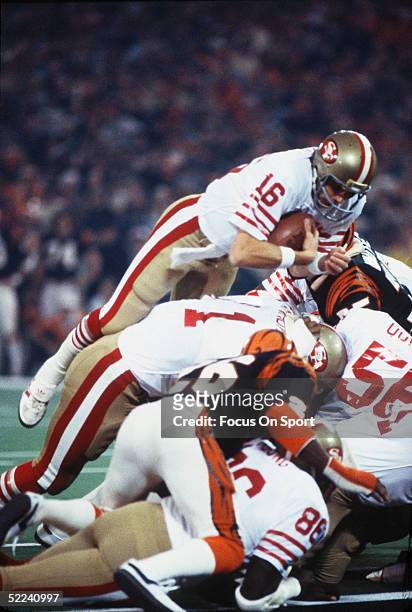 Joe Montana of the San Francisco 49ers dives over a pile of players to gain yardage against the Cincinnati Bengals during Superbowl XVI at the...