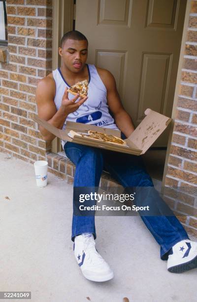 University of Auburn's Center Charles Barkley sits on his doorstep and eats a slice of pizza in a circa 1980s photo.