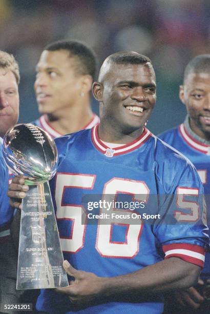 New York Giants' Lawrence Taylor holds the Super Bowl XXI trophy.