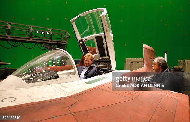 Britain's Prince Harry sits in an A-wing fighter as he talks with US actor Mark Hamill during a tour of the Star Wars sets at Pinewood studios in...