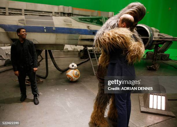 Britain's Prince William, Duke of Cambridge is hugged by Chewbacca as British actor John Boyega smiles during a tour of the Star Wars sets at...