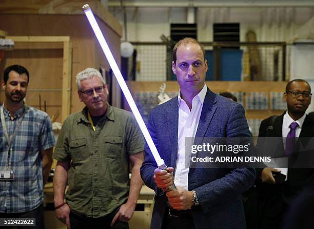 The Duke of Cambridge, Prince William holds a light sabre during a visit to the Star Wars film set at Pinewood Studios near Iver Heath, west of...