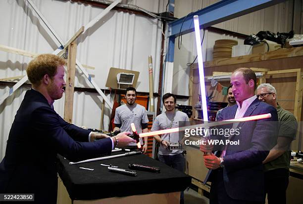 Prince Harry and Prince William, Duke of Cambridge try out light sabres during a tour of the Star Wars sets at Pinewood studios on April 19, 2016 in...
