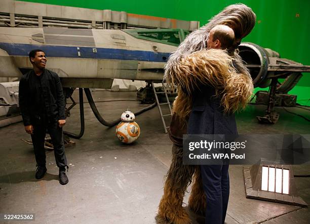 Prince William, Duke of Cambridge is hugged by Chewbacca as British actor John Boyega smiles during a tour of the Star Wars sets at Pinewood studios...