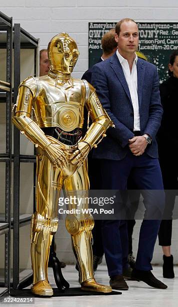 Prince William, Duke of Cambridge poses next to the droid C3P0 from Star Wars as they visit the creature and droid department at Pinewood studios on...