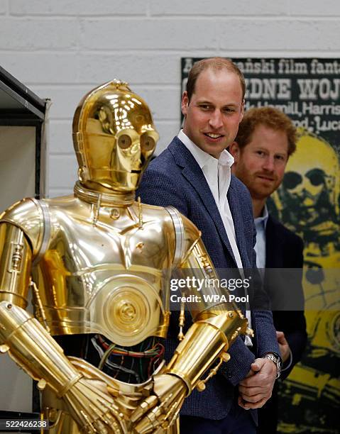 Prince William, Duke of Cambridge and Prince Harry look at the droid C3P0 from Star Wars as they visit the creature and droid department at Pinewood...