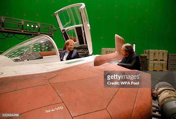 Prince Harry sits in an A-wing fighter as he talks with US actor Mark Hamill during a tour of the Star Wars sets at Pinewood studios on April 19,...