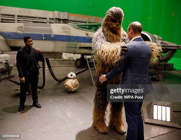 Prince William, Duke of Cambridge is greeted by Chewbacca as British actor John Boyega watches during a tour of the Star Wars sets at Pinewood...