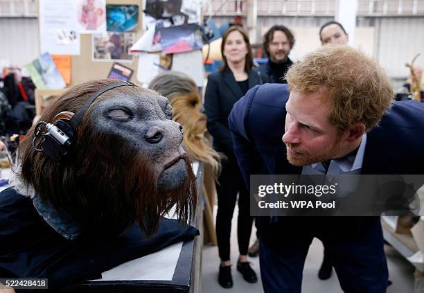 Prince Harry takes a closer look at a robotic mask during a tour of the Star Wars sets at Pinewood studios on April 19, 2016 in Iver Heath, England....