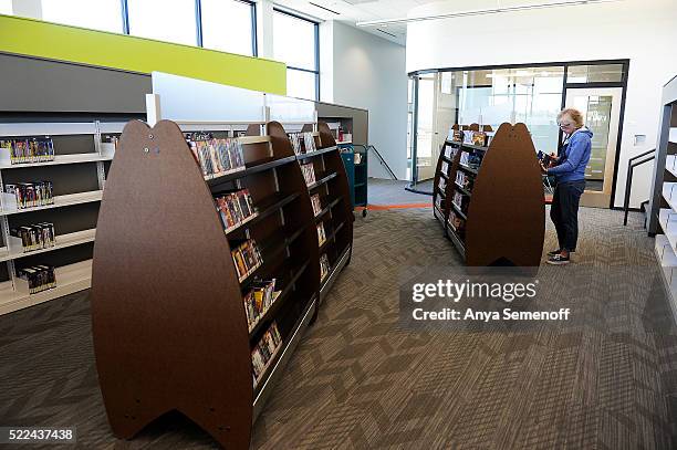 Kelli Bischoff, a material handling technician, shelves movies in the media theater at the new Castle Pines branch for Douglas County Libraries on...