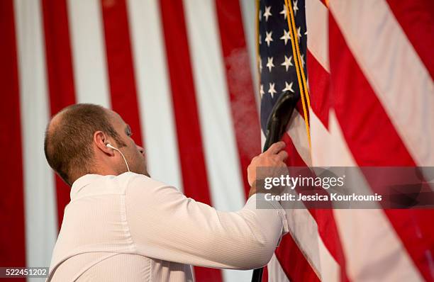 Staff worker for Republican presidential candidate Senator Ted Cruz steams American flags on stage prior to a Pennsylvania kick-off campaign event at...