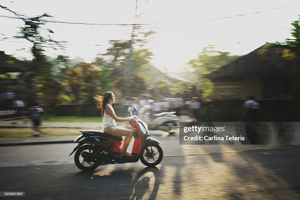 Woman on a motorbike through Balinese Village