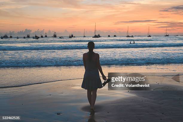 woman walking on the beach at sunset - san juan del sur stock-fotos und bilder