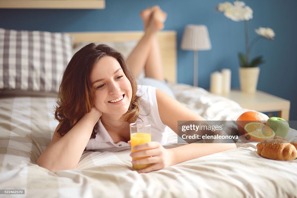 Fille couché sur le lit et petit déjeuner