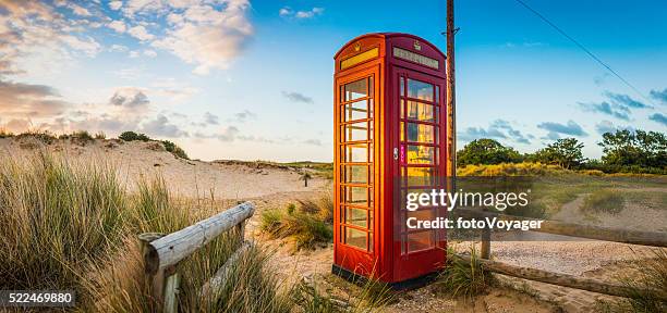 britische rote telefon im feld beleuchtet sonnenaufgang am am meer strand - telefonzelle stock-fotos und bilder