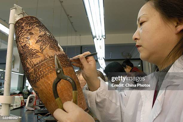 Worker pastes cloisons on a roughcast of a cloisonne vessel at Beijing Enamel Factory on February 24, 2005 in Beijing, China. Cloisonne enamel was...