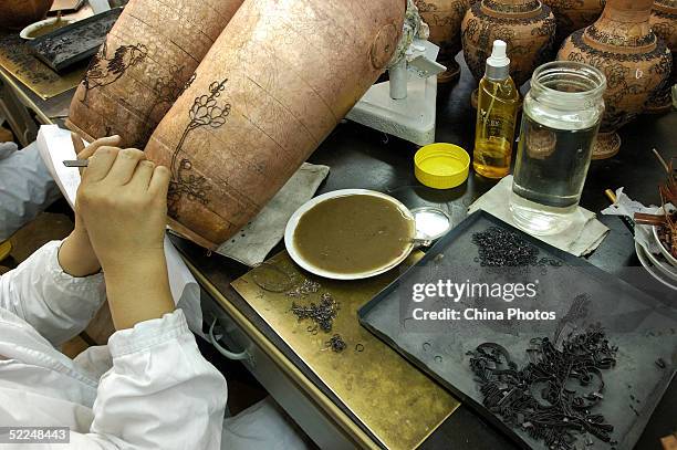 Worker pastes cloisons on a roughcast of a cloisonne vessel at Beijing Enamel Factory on February 24, 2005 in Beijing, China. Cloisonne enamel was...