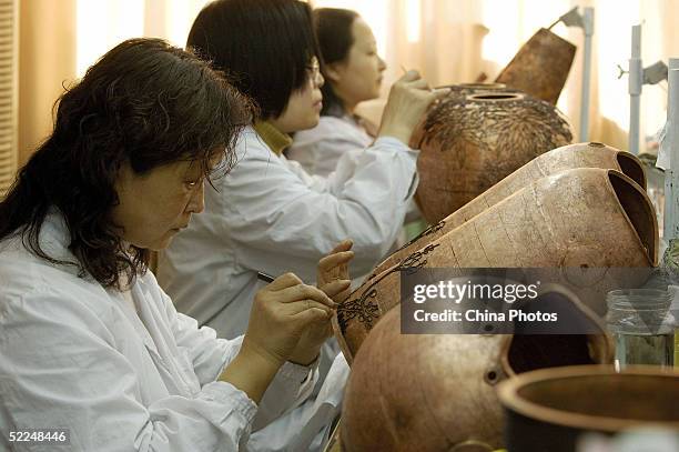 Workers paste cloisons on a roughcast of a cloisonne vessel at Beijing Enamel Factory on February 24, 2005 in Beijing, China. Cloisonne enamel was...