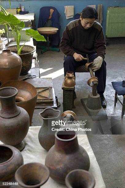 Worker hammers red copper materials to make cloisonne roughcasts at Beijing Enamel Factory on February 24, 2005 in Beijing, China. Cloisonne enamel...