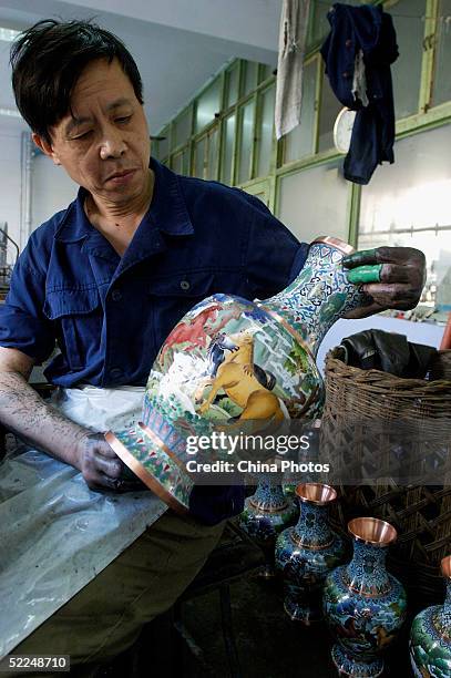 Worker inspects a finished cloisonne ware at Beijing Enamel Factory on February 24, 2005 in Beijing, China. Cloisonne enamel was probably introduced...