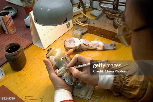 Worker draws lines on a roughcast of jade craftwork at Beijing Jade Carving Factory on February 24, 2005 in Beijing, China. Chinese people believe...