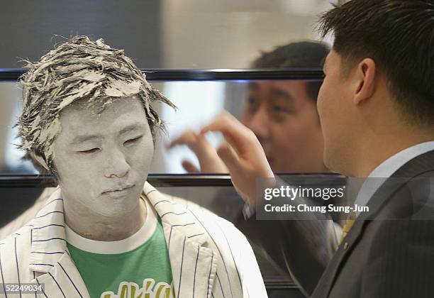 People touch models posing as a mannequins during a promoton for new spring collections in a departement store on February 27, 2005 in Seoul, South...