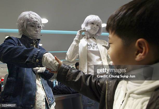 People touch models posing as a mannequins during a promoton for new spring collections in a departement store on February 27, 2005 in Seoul, South...