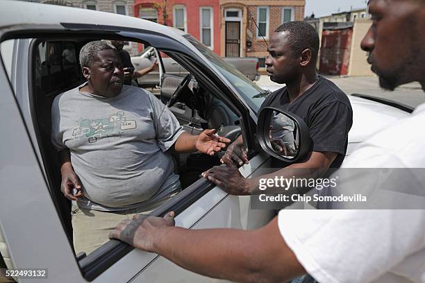 Darren Davis and his cousin Marvin Davis visit with a friend and talk about city and national politics one year after Freddie Gray died April 19,...