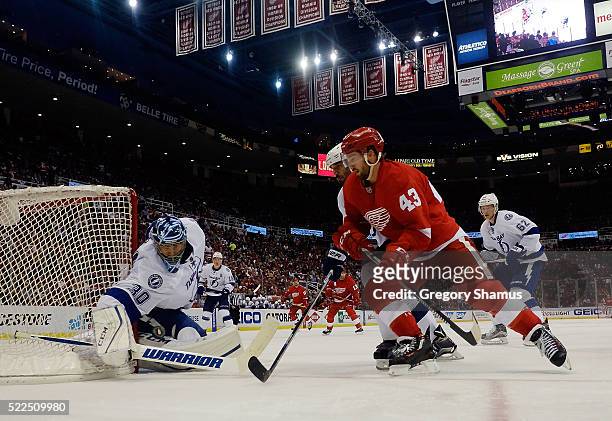 Ben Bishop of the Tampa Bay Lightning tries to control the puck with Darren Helm of the Detroit Red Wings looking for a rebound during the third...