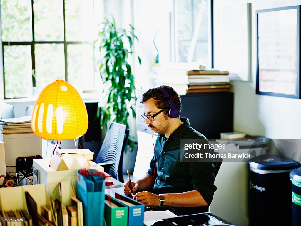 Designer wearing headphones working on tablet